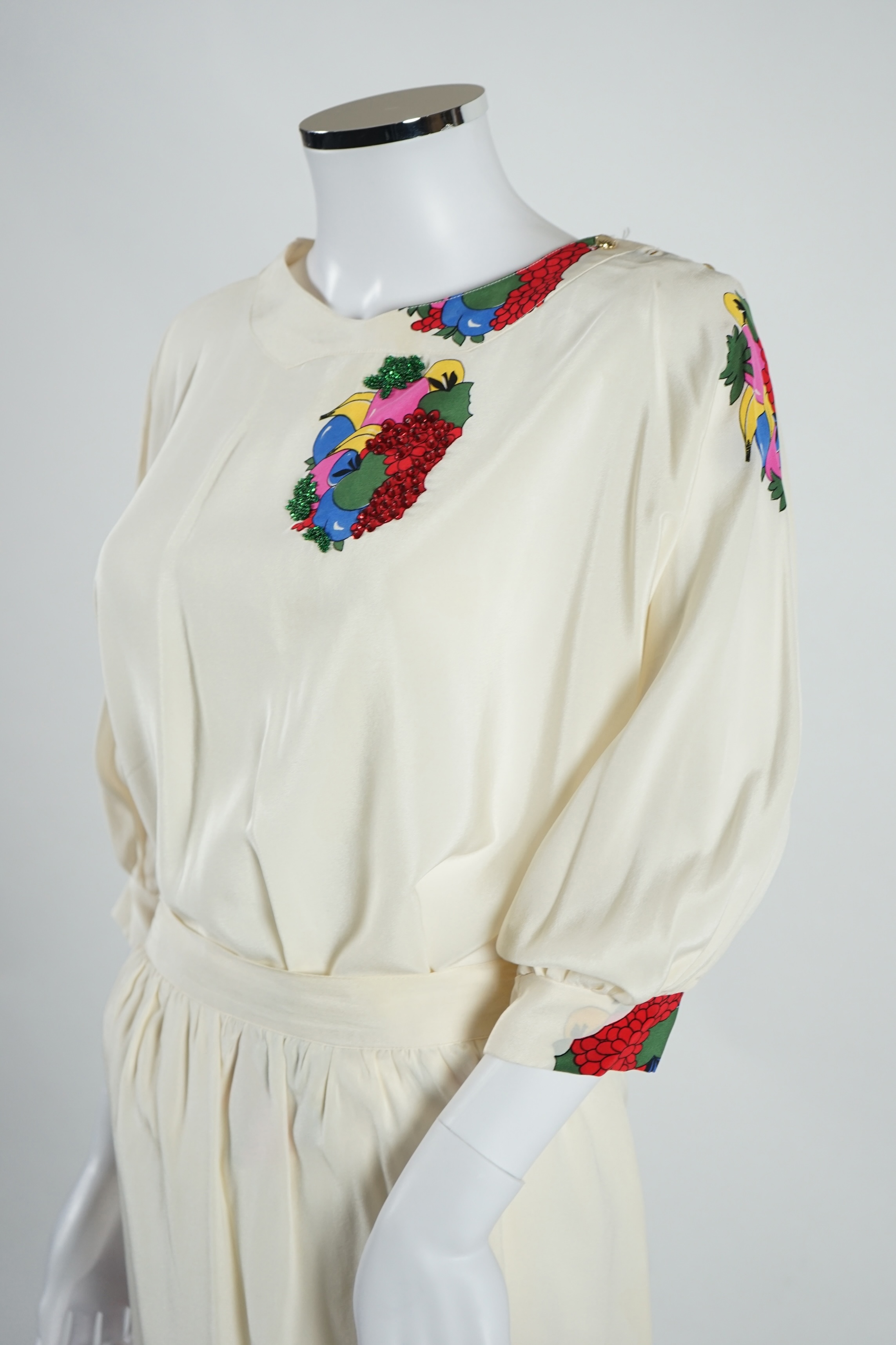 A lady's Angela Caputi silk cream skirt and blouse with fruit design size 46, a Ted Baker white lightweight cardigan with leaf design to the back size 4, a Rawhide dusky pink long laser cut coat size 14 and a Georgina vo